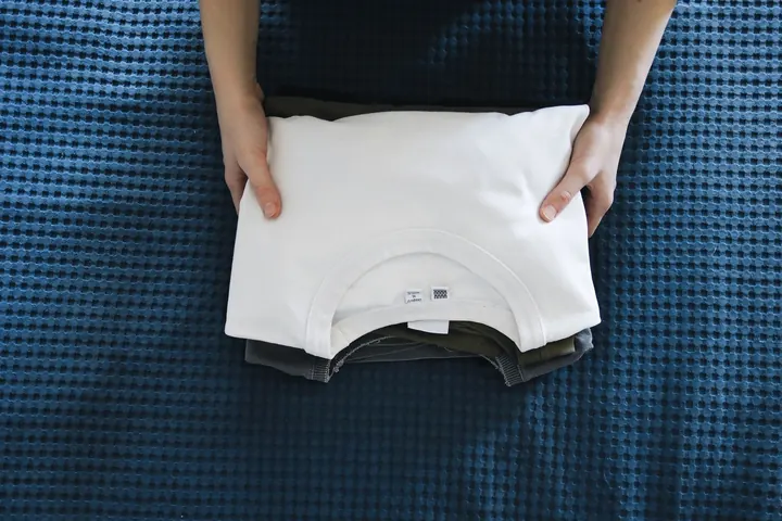 A neatly folded white shirt on a blue blanket
